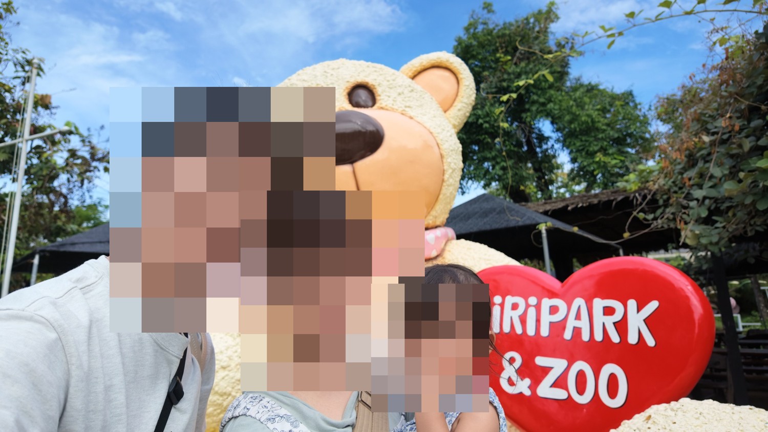 Siri Park & Zooの大きなクマと赤い看板の前で撮った家族写真