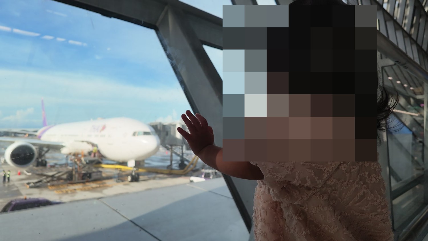 帰国日にスワンナプーム空港の窓から飛行機を見る娘